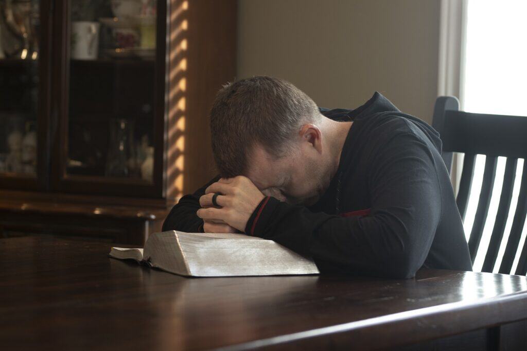 Man bowed in prayer over Bible