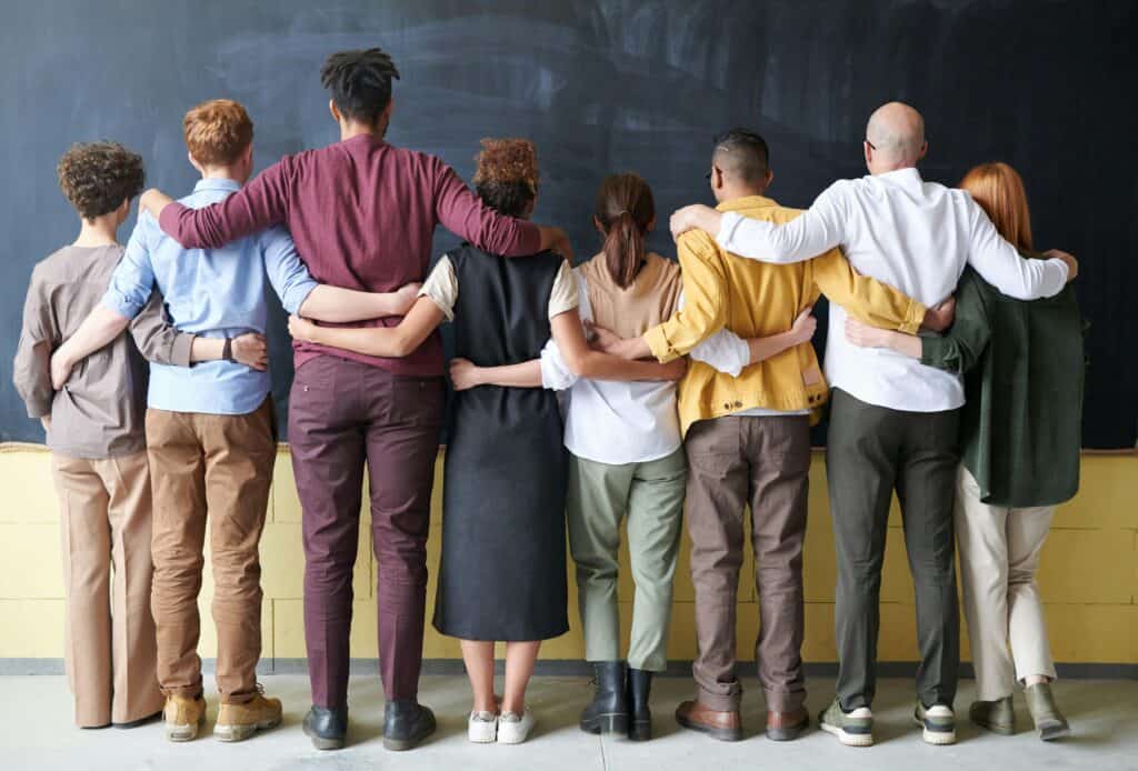 backs of racially diverse group of people arms around each other
