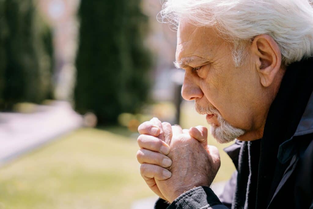older man hands folded grief sadness
