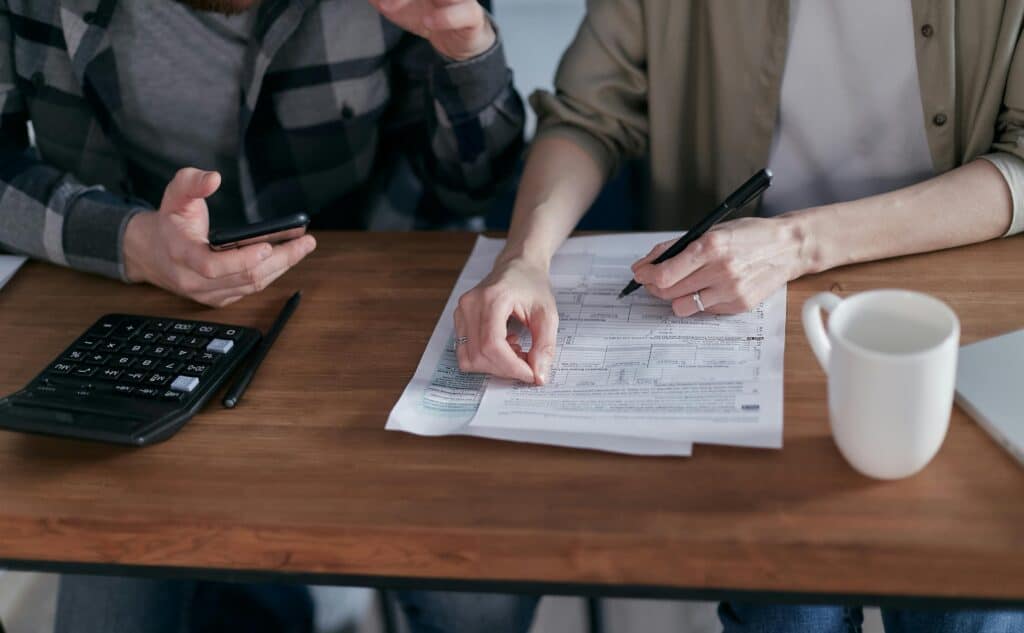 hands of couple with paperwork and calculator