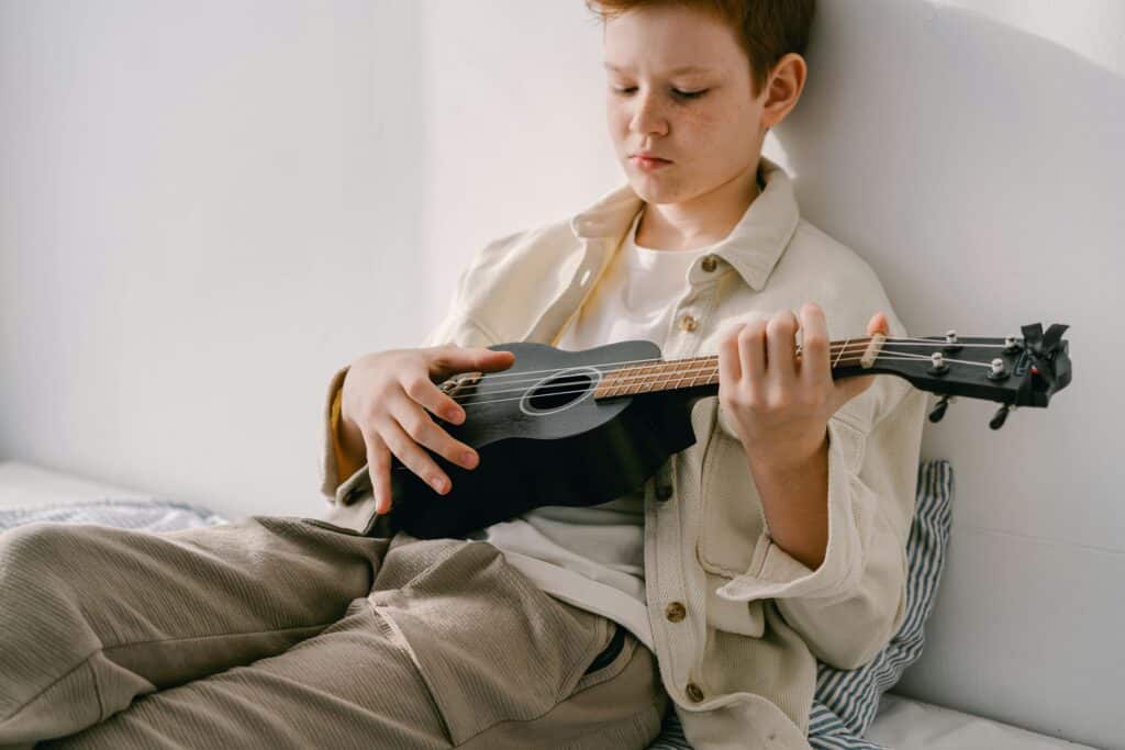 tween boy playing ukulele