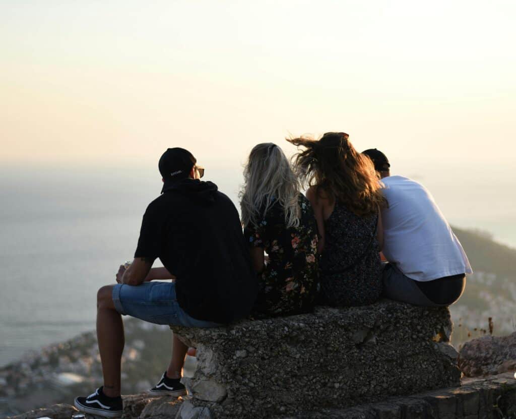 two men two women looking out over ocean at sunset