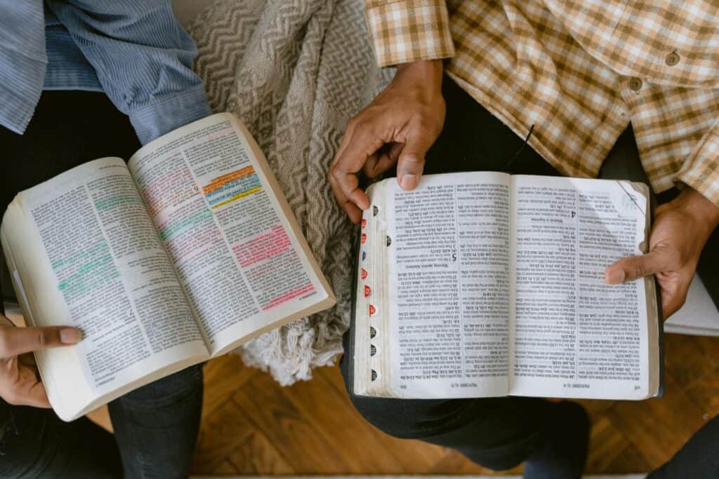 two sets of male hands holding Bibles